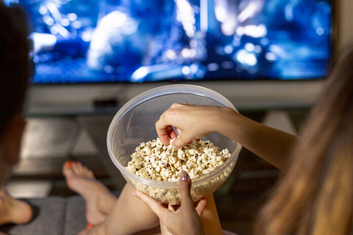 zblizen-ludzie-je-popkorn-w-zywym-pokoju_Easy-Resize.com Jak zrobić domowe kino w salonie? | Domowe kino | Aj Wykończenia – Budownictwo, Dom i Ogród